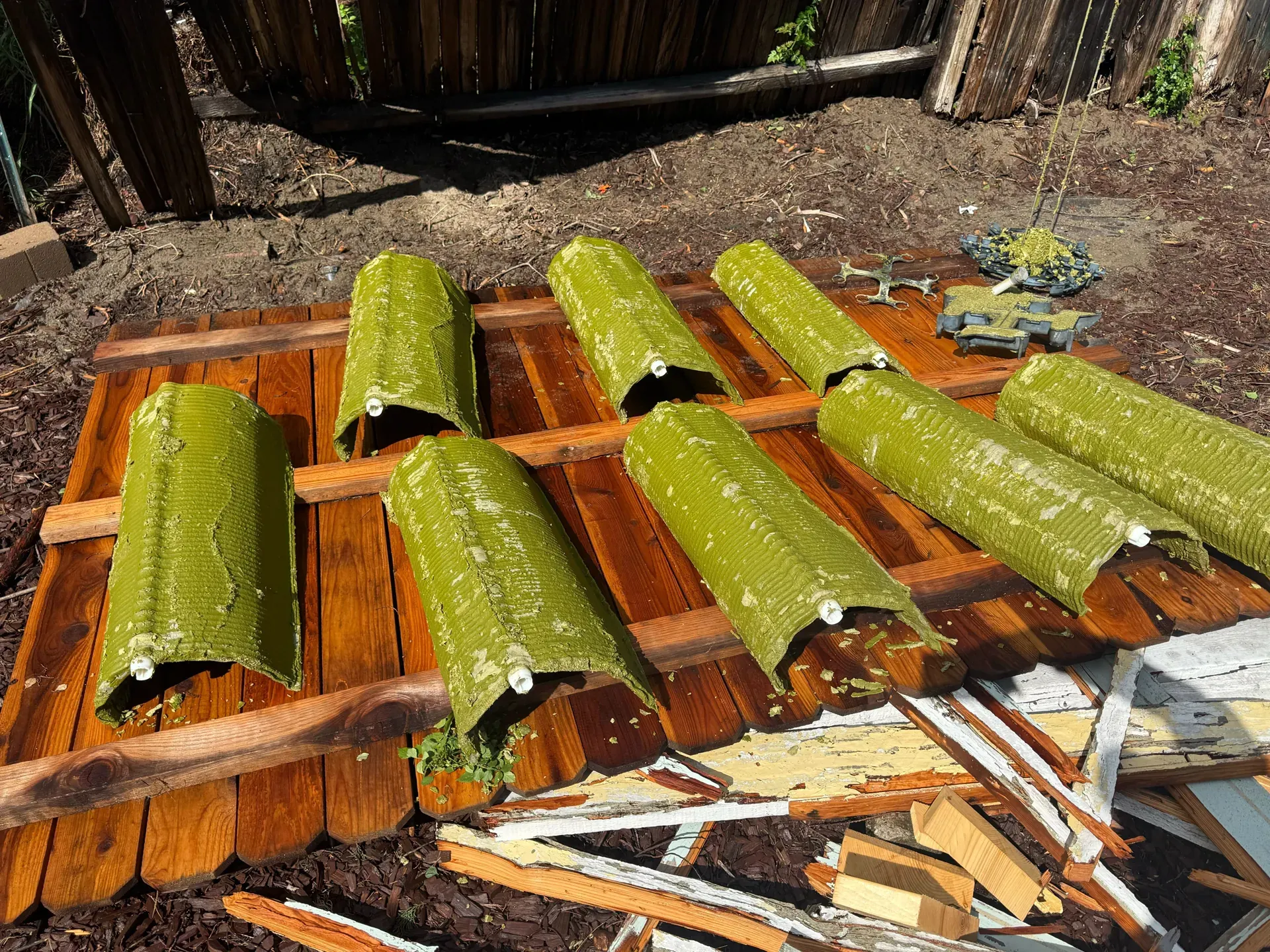 Pool filter cartridges coated in green algae, set out on wood to dry