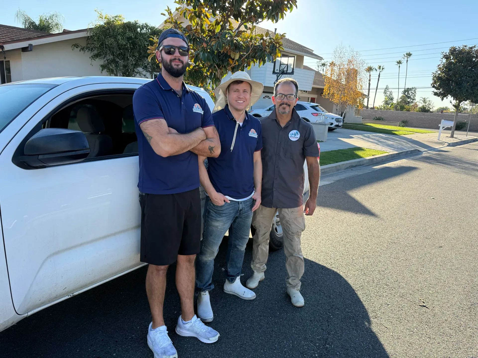 Three Orange County Pool Cleaners technicians posing in front of the company truck