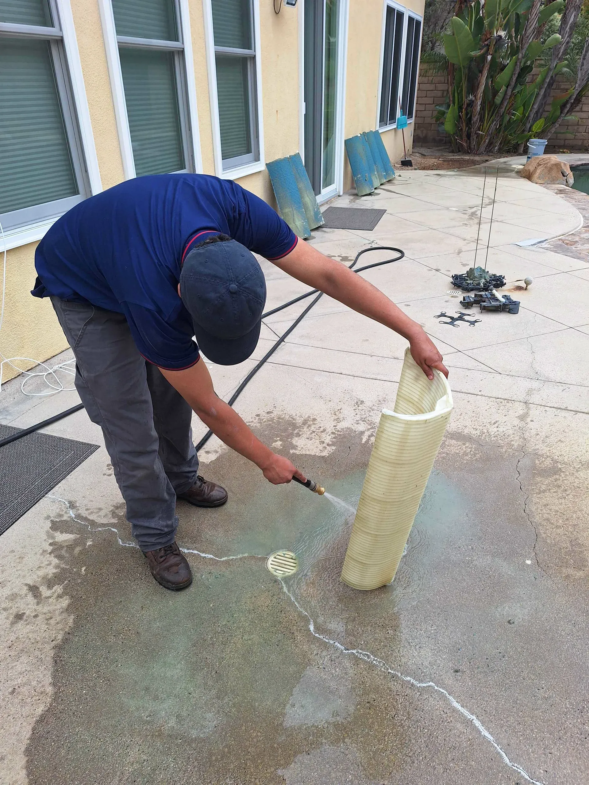 A technician rinsing a pleated pool filter cartridge with a hose
